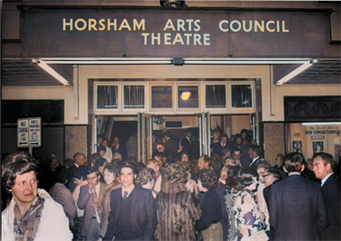 a crowd of people in seventies clothing in front of the Horsham Theatre