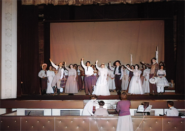 performers on stage in costume with arms raised