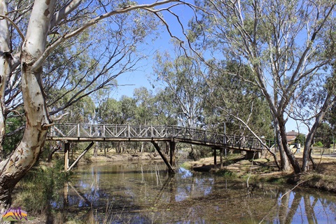 A small footbridge crossing the river surrounded by trees
